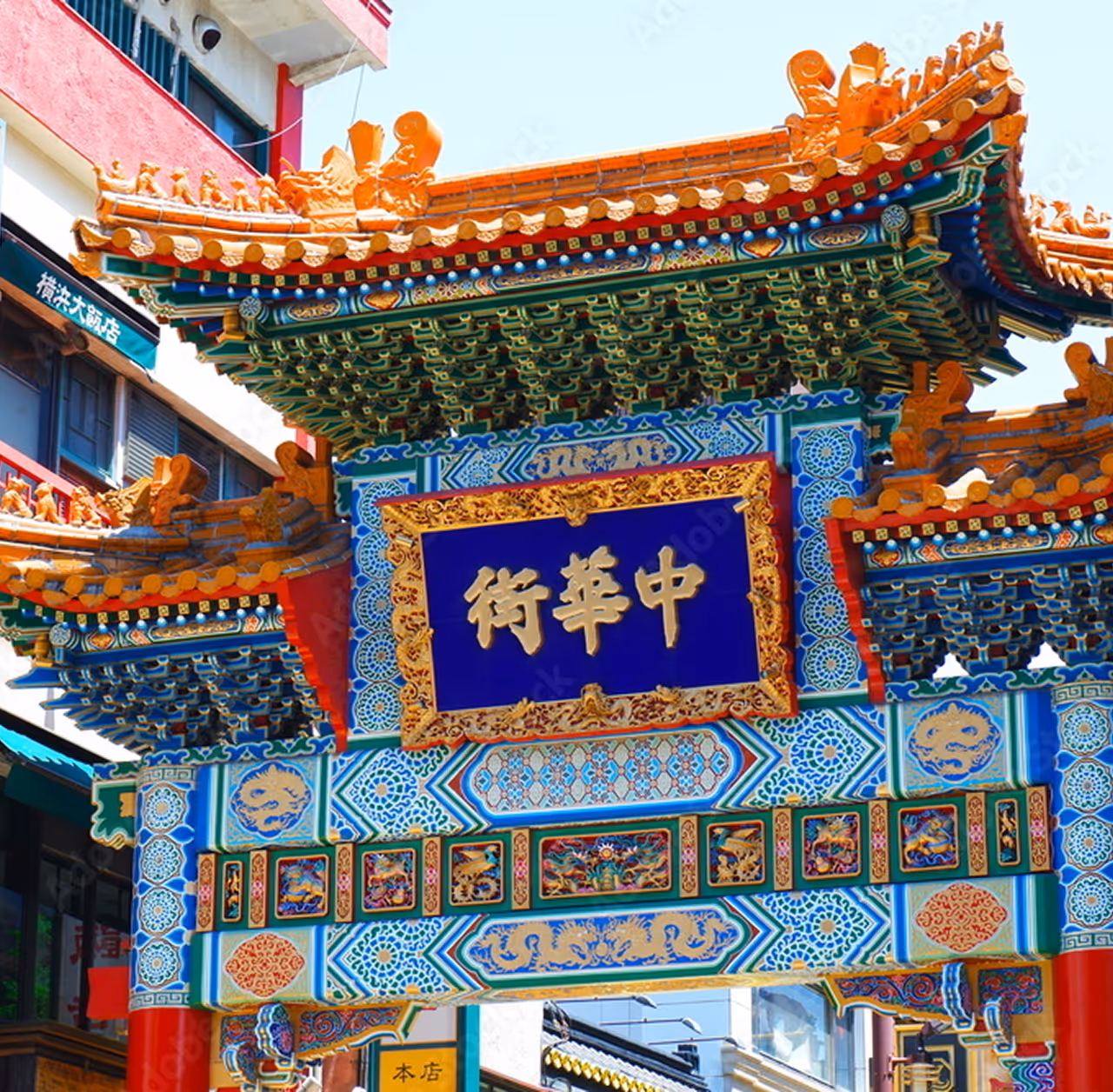 Colorful traditional Chinese gate with ornate carvings and a blue sign featuring gold Chinese characters.