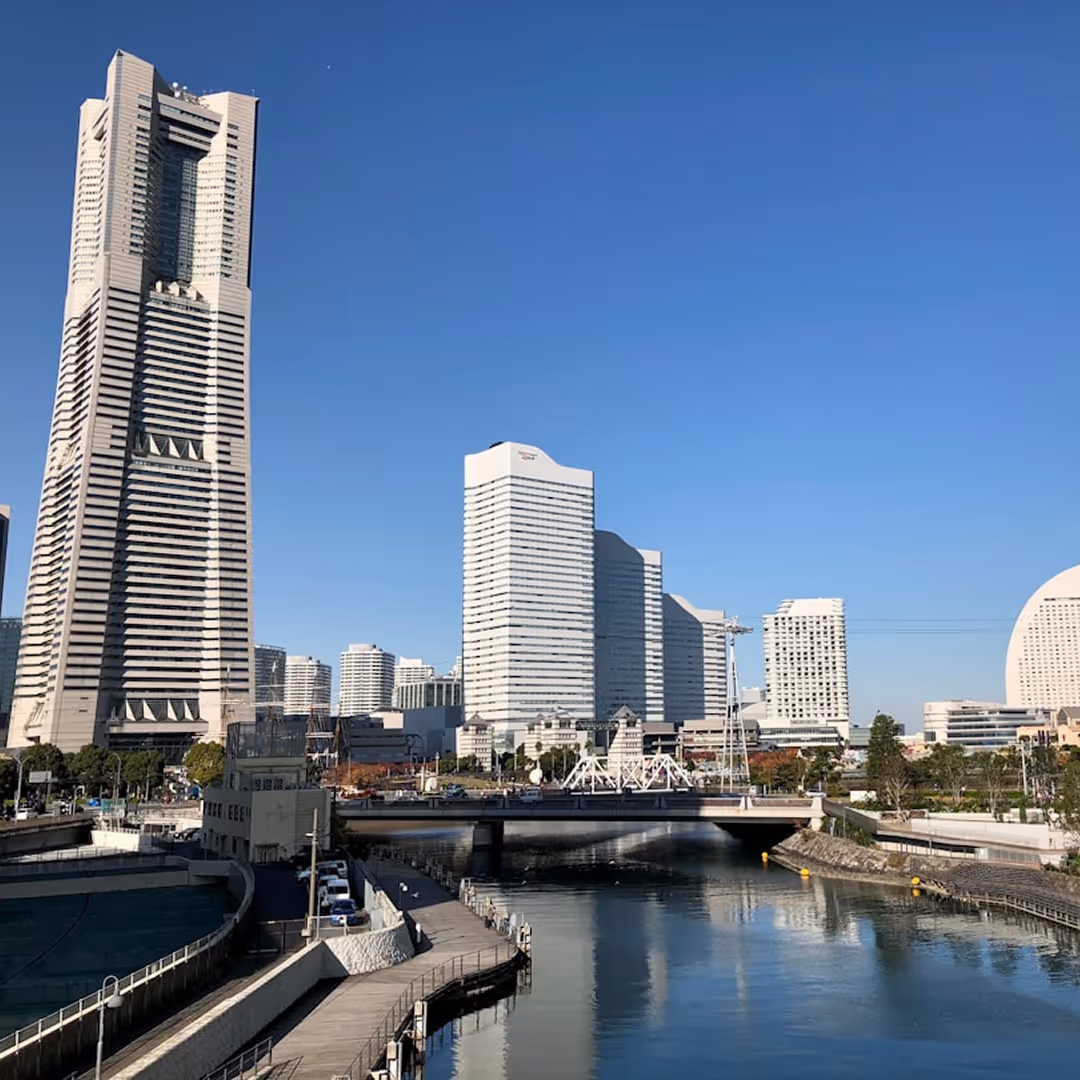 Modern cityscape of Yokohama with high-rise buildings and a canal under a clear blue sky.